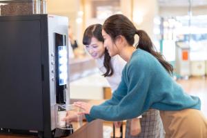 Dos mujeres están mirando un monitor de computadora en Hotel S-plus Nagoya Sakae, en Nagoya