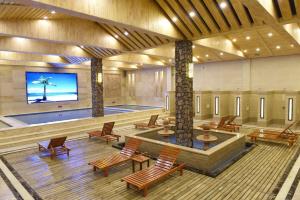 a large lobby with a pool and chairs and a tv at 7Days Inn Hulu Island Xingcheng University Town Branch in Huludao