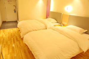 two beds in a hotel room with white sheets at 7Days Inn Neijiang Longchang Xinhua Street Branch in Neijiang