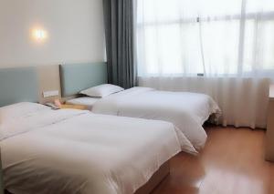 Postel nebo postele na pokoji v ubytování 7Days Inn Rongjiang Binjiang Avenue Branch