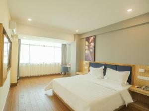 a bedroom with a large white bed and a window at 7Days Inn Sanya Yalong Bay Branch in Sanya