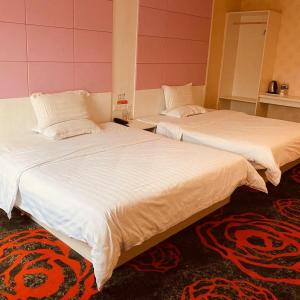 two beds sitting next to each other in a room at 7Days Inn Yancheng Binhai Renmin Middle Road Darunfa Branch in Binhai