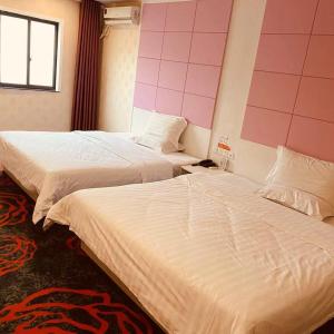 two beds in a hotel room with pink walls at 7Days Inn Yancheng Binhai Renmin Middle Road Darunfa Branch in Binhai
