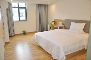 Un dormitorio con una gran cama blanca y una mesa en 7Days Inn Anqing Train Station Branch, en Anqing