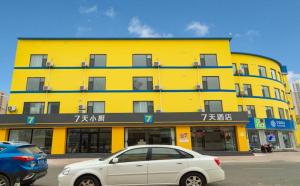 un bâtiment jaune avec une voiture garée devant lui dans l'établissement 7Days Inn Dongying Taihangshan Road Business Park Branch, à Dongying
