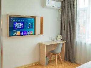 1 dormitorio con escritorio y TV en la pared en 7Days Inn Dongying Taihangshan Road Business Park Branch, en Dongying