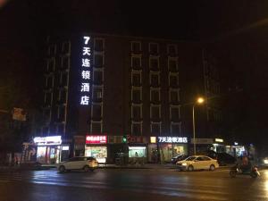 un edificio di notte con auto parcheggiate di fronte di 7Days Inn Chengdu Wuhou Temple Jinli Orthopedic Hospital Subway Station Branch a Chengdu