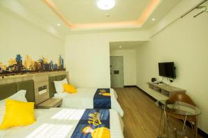 ein Hotelzimmer mit zwei Betten und einem Fernseher in der Unterkunft 7 Days Inn Haikou East Train Station North and South Fruit Market Fengxiang Road Branch in Haikou