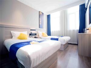two beds in a hotel room with blue curtains at 7Days Inn Hengshui Hengbai International Branch in Hengshui