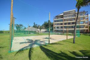 a tennis court with a net in front of a building at Beach Living Apartment in Aquiraz