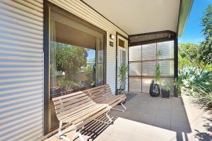 un banco de madera sentado en el porche delantero de una casa en Townhouse 3 en Broken Hill