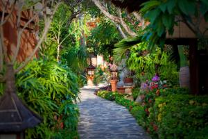 a stone path in a garden with flowers and plants at Puri Mas Boutique Resort & Spa in Senggigi