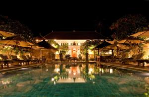 a swimming pool with chairs and a house at night at Puri Mas Boutique Resort & Spa in Senggigi