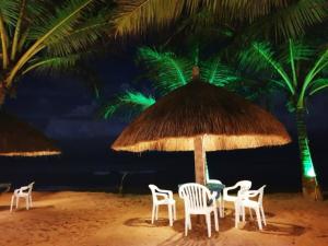 a table and chairs under a straw umbrella on the beach at Oasey Ayurveda Hotel in Bentota