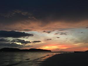 una puesta de sol en una playa con el océano en House of Lion Hostel, en Pantai Cenang