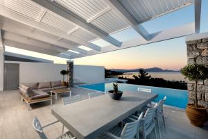 a patio with a table and chairs and a couch at Villa Estella with pool & jacuzzi in Lindos in Líndos