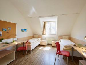 a room with two beds and a desk and chairs at Gästehaus des GOETHE-Institut Freiburg in Freiburg im Breisgau