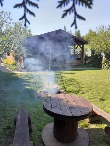 Majowy Domek في Posada Górna: شواية بطاولة خشبية يخرج منها الدخان