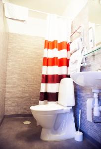 uma casa de banho com uma cortina de chuveiro vermelha e branca e um WC. em Lilla Hotellet em Vilhelmina