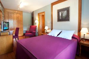 een slaapkamer met een groot paars bed en een stoel bij Hotel Diamó in Castejón de Sos