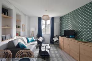 a living room with a couch and a tv at Cap à l'Ouest by Cocoonr in Saint Malo +8 photos
