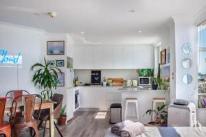 a kitchen with white cabinets and a table and chairs at Oh My Beach View - Top Floor Paradise by Sydney Dreams Serviced Apartment Bondi in Sydney