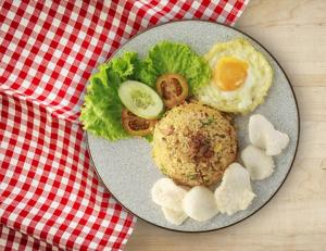 a plate of food with an egg on a table at OYO 1662 Zury Homestay in Kuta Lombok