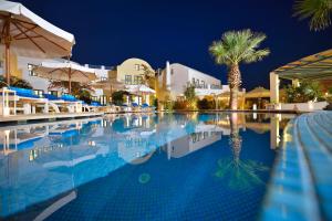 a swimming pool at a resort at night at Tamarix Del Mar Suites in Kamari