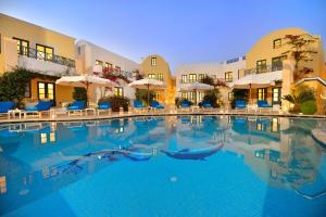 a large pool with chairs and umbrellas in a hotel at Tamarix Del Mar Suites in Kamari