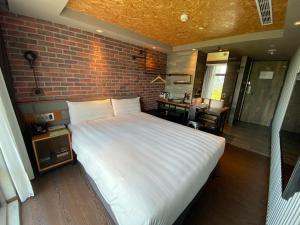 una camera con un letto bianco e un muro di mattoni di City Suites - Kaohsiung Pier2 a Kaohsiung