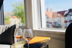two glasses of wine on a table with a window at Cwtch Guesthouse in Llandudno
