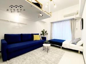 OUCHI HOTEL Higashi-Hiratsuka #302 في هيروشيما: غرفة معيشة مع أريكة زرقاء وسرير