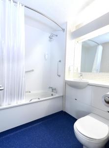 a bathroom with a toilet and a tub and a sink at Travelodge Waterford in Waterford