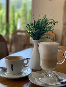 duas chávenas de café e um vaso numa mesa em Садиба "Градний Узвіз" em Tatariv
