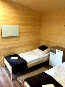 sypialnia z 2 łóżkami w pokoju z drewnianymi ścianami w obiekcie Sarzynówka pod Świerkiem w Krasnobrodzie