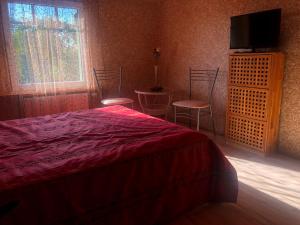 a bedroom with a bed and two chairs and a television at Sunny seaside place in Jūrmala