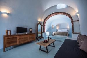 a living room with a bed and a tv and a couch at Elia 1968 Cave Houses in Oia