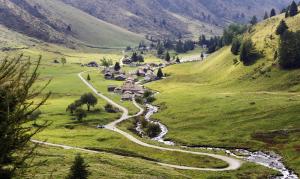 um vale montanhoso sinuoso com um rio e uma aldeia em Baita Mirellina - Case di Viso em Ponte di Legno
