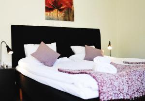 a bedroom with two beds with white sheets and purple pillows at Kågeröds Värdshus Tre Stjärnor in Kågeröd