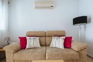 Un sofá marrón con almohadas rojas y blancas. en Hostly Lagar Center-Fibre-Parking optional-CLess en Sevilla