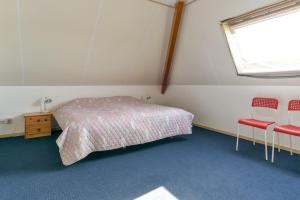 a bedroom with a bed and two red chairs at vakantiehuis op terschelling in Baaiduinen