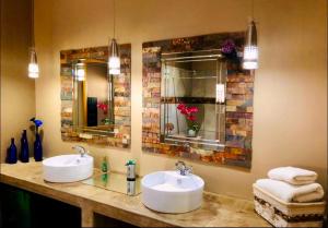two sinks in a bathroom with two mirrors at Rooibos Retreat in Richards Bay
