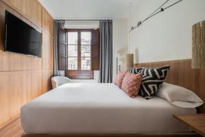 a bedroom with a large white bed with pillows at Toc Hostel Granada in Granada