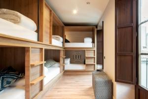 a room with wooden bunk beds with a couch at Toc Hostel Granada in Granada