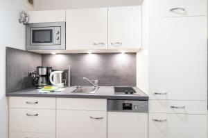 a white kitchen with a sink and a microwave at Ferienwohnung Schmid in Oberstdorf +2 photos