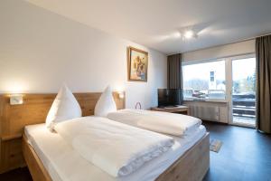a bedroom with a large white bed with a window at Ferienwohnung Schmid in Oberstdorf