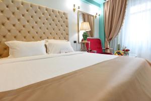 a bedroom with a large white bed with a large headboard at Phoenicia Grand Hotel in Bucharest