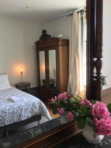 ein Schlafzimmer mit einem Bett und einer Vase mit rosa Blumen in der Unterkunft La Maison de famille in Boën