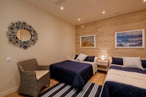 a bedroom with two beds and a chair and a mirror at Gran casa al lado de la playa y Barcelona Centro in Badalona