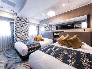 a hotel room with two beds and a tv at APA Hotel Shin Osaka Ekimae in Osaka
